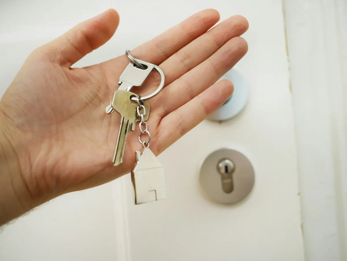 Hand met een sleutelbos voor een deur met een cilinderslot