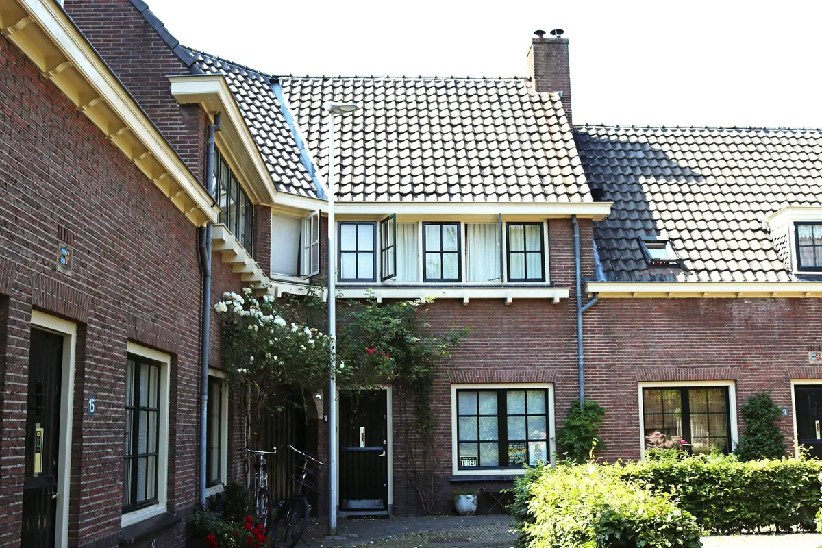 Bakstenen woningen met pannendaken rond een hofje