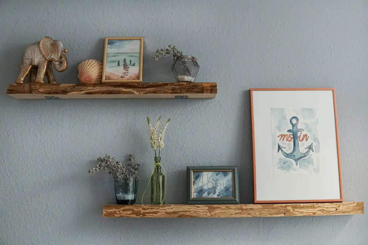 Twee houten wandplanken met vaasjes en lijstjes aan een blauwgrijze muur