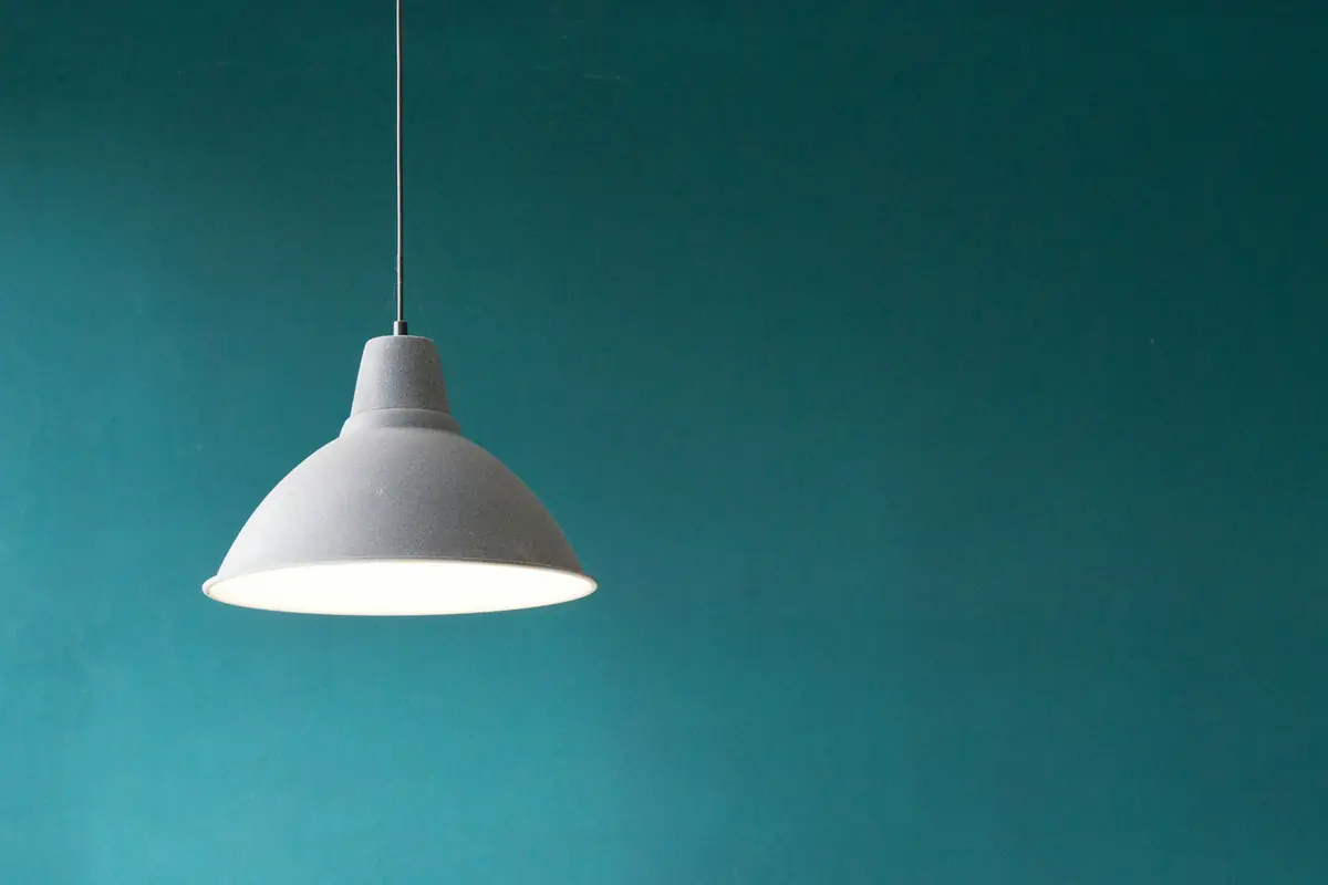 Witte hanglamp voor een petrolblauwe muur