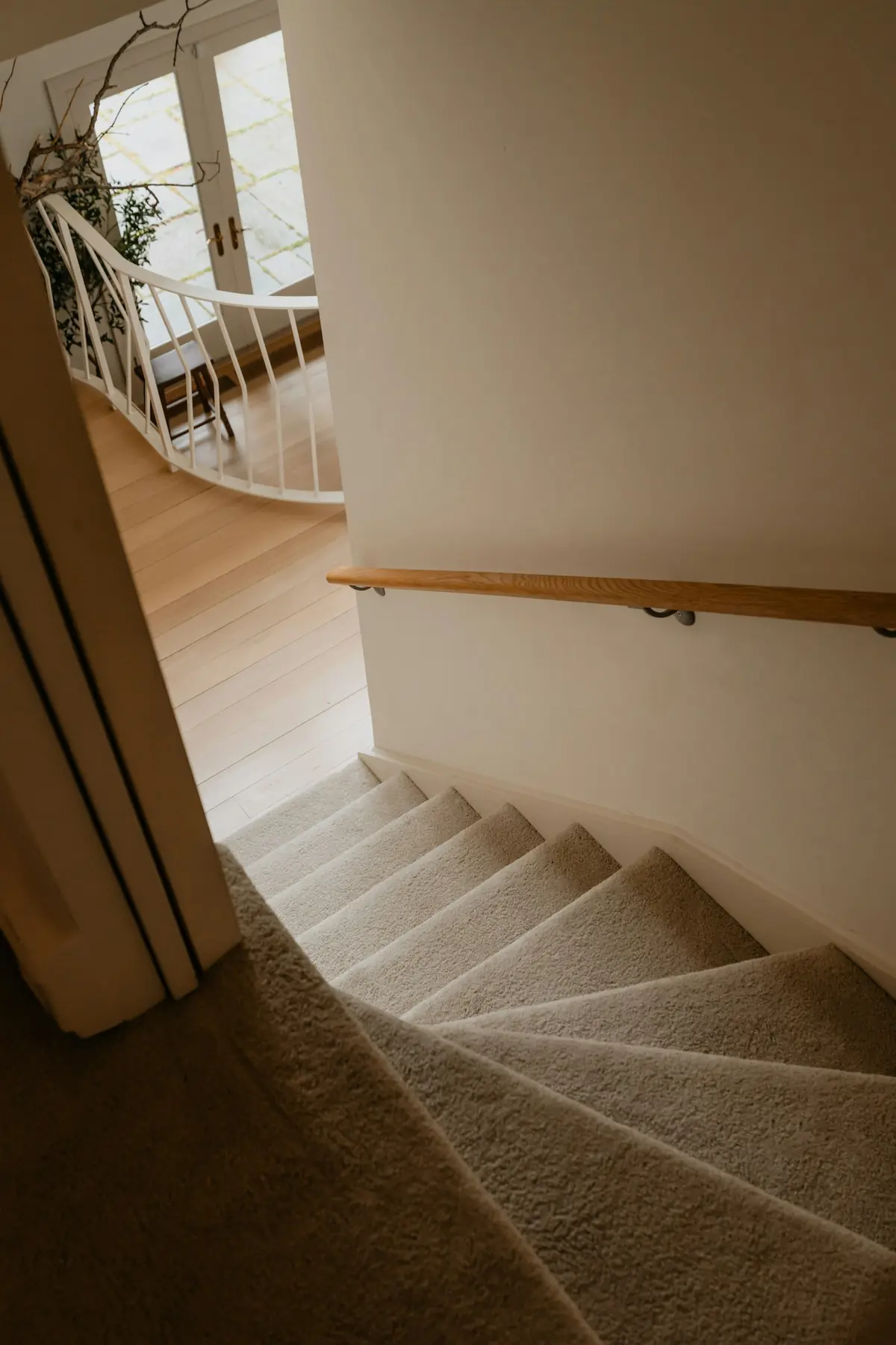 Houten trapleuning langs de muur van een trap met vloerbedekking