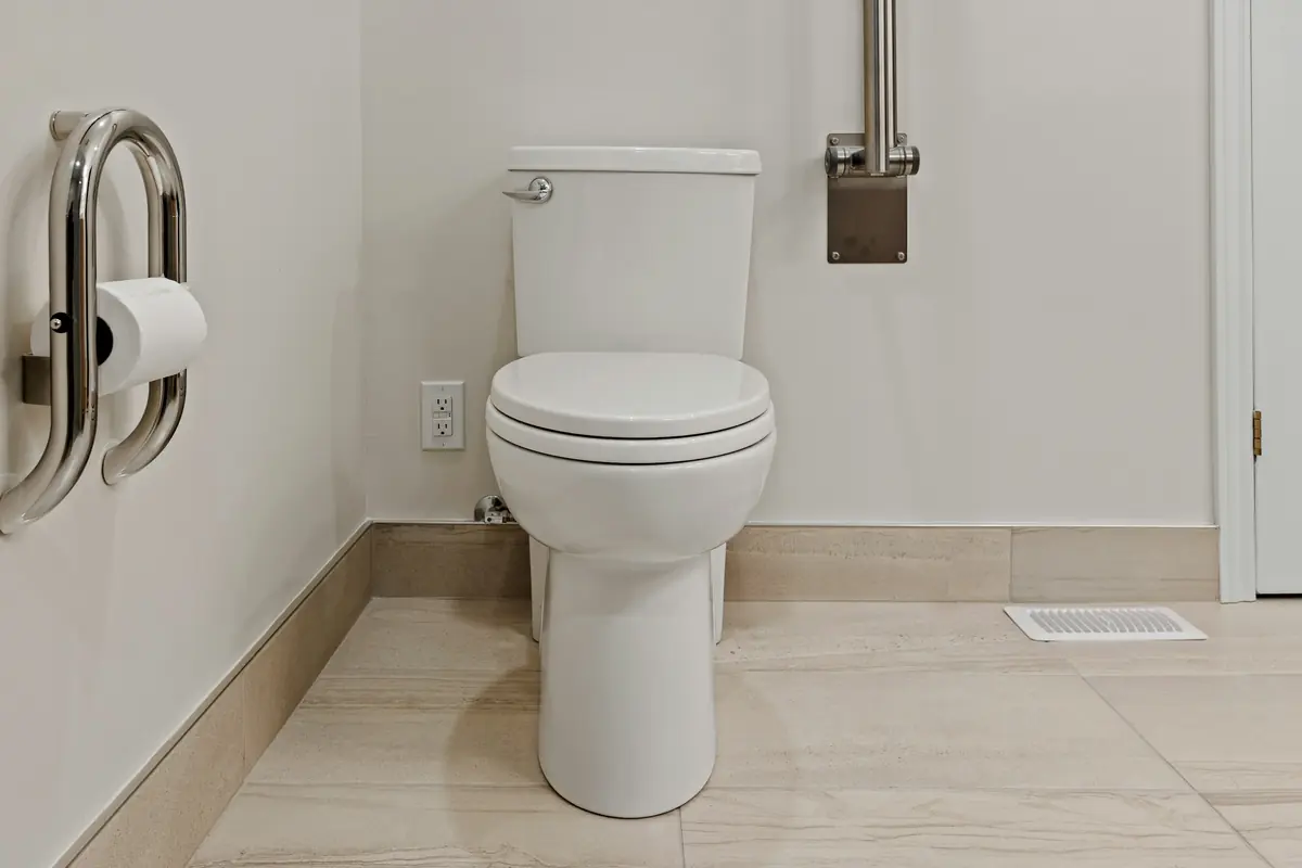 Staand toilet met steunbeugels aan beide kanten in een lichte badkamer