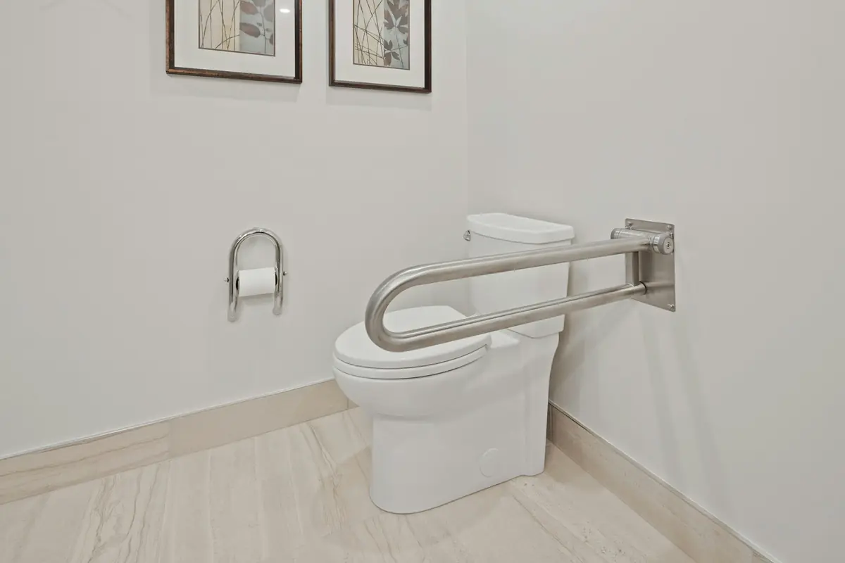 Opklapbare wandbeugel naast een toilet in een lichte badkamer